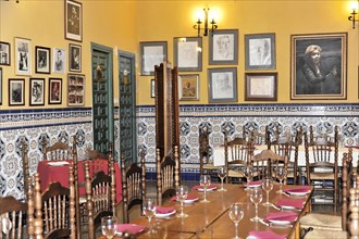 Jaen, Empty restaurant with tables, chairs and portraits on wall tiles, Jaen, Andalusia, Spain,
