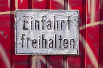 White, old sign Keep driveway clear on a red garage door, Germany, Europe