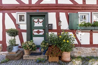 Old half-timbered house, decorated with flowers, carved entrance door, idyllic alley, old town,