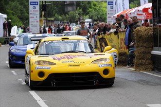 A yellow racing car with a racing driver at a sporting event, surrounded by spectators, SOLITUDE