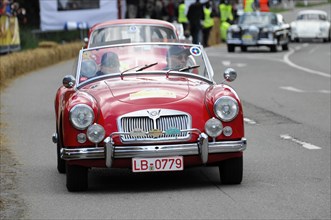 A red MG vintage convertible drives on a road at a racing event, SOLITUDE REVIVAL 2011, Stuttgart,