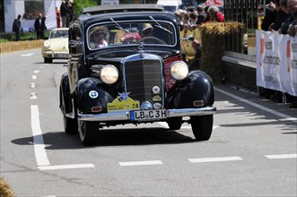A classic Mercedes vintage car drives past spectators at a sunny road race, SOLITUDE REVIVAL 2011,