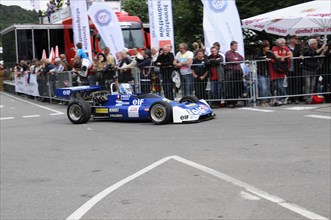 Blue racing car in the foreground with team and advertising banners in the background, SOLITUDE