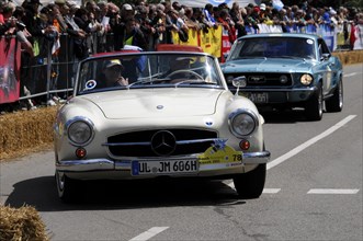 A white Mercedes-Benz vintage cabriolet drives in front of spectators at a road race, SOLITUDE