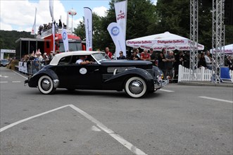 Black classic car takes part in a classic car rally, surrounded by spectators, SOLITUDE REVIVAL