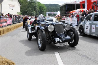 A black classic racing car is surrounded by spectators at the starting line, SOLITUDE REVIVAL 2011,