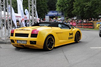 Rear view of a yellow Lamborghini sports car at a car race with spectators in the background,