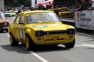 A yellow sports car with rally start number in front of spectators on a race track, SOLITUDE