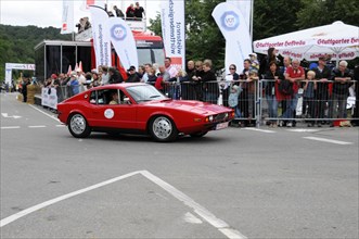A red old sports car drives on a race track, applauded by a crowd, SOLITUDE REVIVAL 2011,