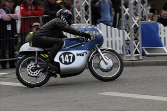 Motorcyclist at full speed on a race track with spectators in the background, SOLITUDE REVIVAL