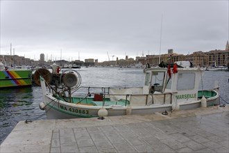 Marseille, Boat at the quay in the harbour of Marseille with calm water surface and city view in