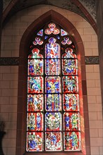 Speyer Cathedral, A detailed stained glass window in red and blue with biblical motifs floods the