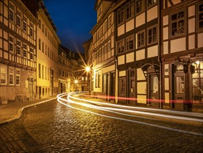 Street with half-timbered houses and cobblestones in the historic old town at dusk, Halberstadt,