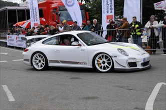 A white Porsche 911 sports car drives past spectators at a racing event, SOLITUDE REVIVAL 2011,