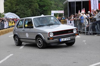 A black and red Volkswagen GTI classic car at a rally, surrounded by spectators, SOLITUDE REVIVAL