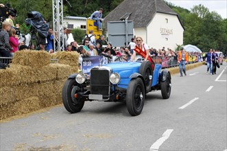 An old racing car is accompanied by a person with a flag, spectators watch the event, SOLITUDE