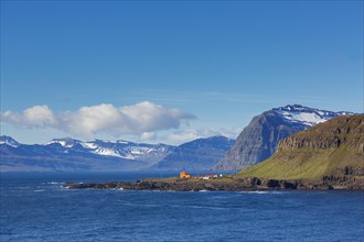 Rugged mountains and orange lighthouse at Skalanes along the fjord Seyoisfjoerour, Seydisfjoerdur