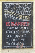Sign outside pub advising that handshaking and touching is prohibited during the song Sweet