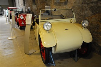Deutsches Automuseum Langenburg, A small white vintage car in a museum, next to an information