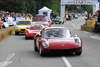 A red Abarth racing car drives on a road race track with spectators on the side, SOLITUDE REVIVAL