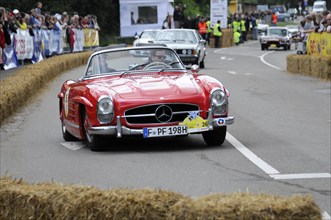 A red Mercedes 300SL Roadster on a race track, accompanied by spectators, SOLITUDE REVIVAL 2011,
