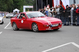 A red classic sports car takes part in a vintage car race, surrounded by spectators, SOLITUDE