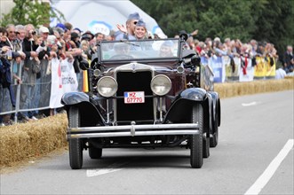 Dark antique car in a parade with passenger waving to the crowd, SOLITUDE REVIVAL 2011, Stuttgart,
