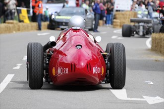 Rear view of a red historic racing car on the road with driver in helmet, SOLITUDE REVIVAL 2011,
