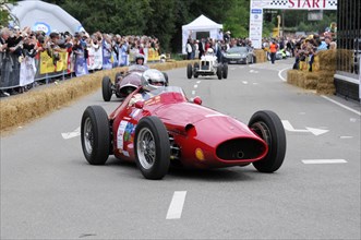 A red classic formula racing car drives past spectators on a cordoned-off road, SOLITUDE REVIVAL