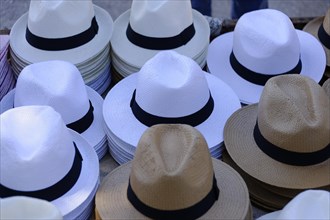 The bay of Port Miou in Cassis, pile of white and natural-coloured hats on a market stall,