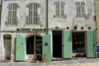 Marseille, Old building facade with green shutters and a small French-style shop, Marseille,