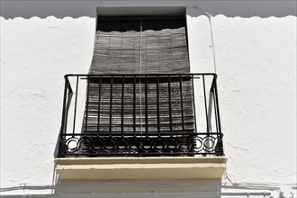 Solabrena, blinds protect a balcony window on a white building from the intense sun, Andalusia,