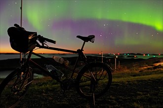 Northern lights (aurora borealis) mingle with sunset, bike without luggage, Lovunden, Helgeland