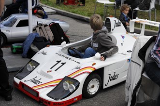 A child plays in a white Porsche replica at a motorsport event, SOLITUDE REVIVAL 2011, Stuttgart,