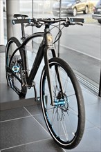 Modern e-bike (Porsche) with black frame and blue design elements in the showroom, Schwaebisch