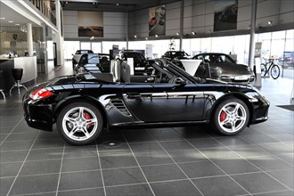 A black Porsche Cabriolet with an open roof stands in the showroom, Schwaebisch Gmuend,