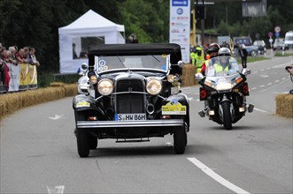 A black vintage car at a racing event escorted by a police motorbike, SOLITUDE REVIVAL 2011,