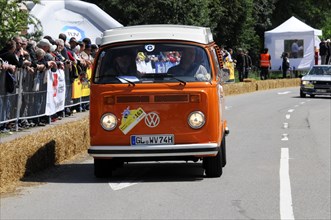 An orange Volkswagen bus drives past a crowd at a race, SOLITUDE REVIVAL 2011, Stuttgart,