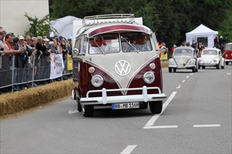 A two-coloured vintage Volkswagen bus drives on the road in front of spectators, SOLITUDE REVIVAL