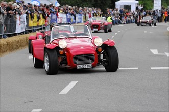 A red vintage sports car drives through a crowd at a street race, SOLITUDE REVIVAL 2011, Stuttgart,