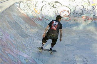 Teenager skateboarding on a ramp in a skate park decorated with graffiti, Marseille,