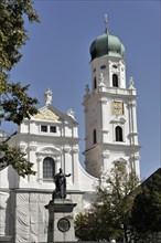St Stephan Cathedral, Passau, White baroque church with high tower and a statue in the foreground,