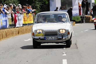 A white BMW classic car drives in front of a crowd during a street race, SOLITUDE REVIVAL 2011,