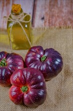 Group of tasty fresh tomatoes of the blue variety on a burlap cloth with a bottle of olive oil in