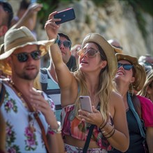 Many tourists stand close together and take selfies with their cell phones, photo quality Job ID: