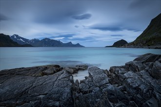 Seascape on the beach at Haukland. View of the mountains of Myrland on Flakstadoya. Dark sky,