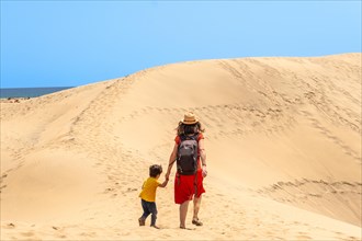Mother and child walking in the dunes of Maspalomas in summer, Gran Canaria, Canary Islands