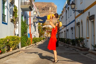 Mother having fun with her raised son in the port of the town Mogan in Gran Canaria. Family