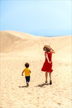 Mother and son tourists enjoying running in the dunes of Maspalomas, Gran Canaria, Canary Islands