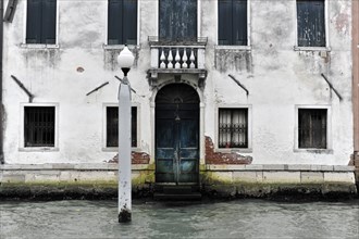 Weathered building on the waterfront in Italy with striking blue door, Venice, Veneto, Italy,
